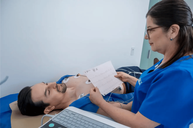 Técnica de salud revisando electrocardiograma a paciente acostado