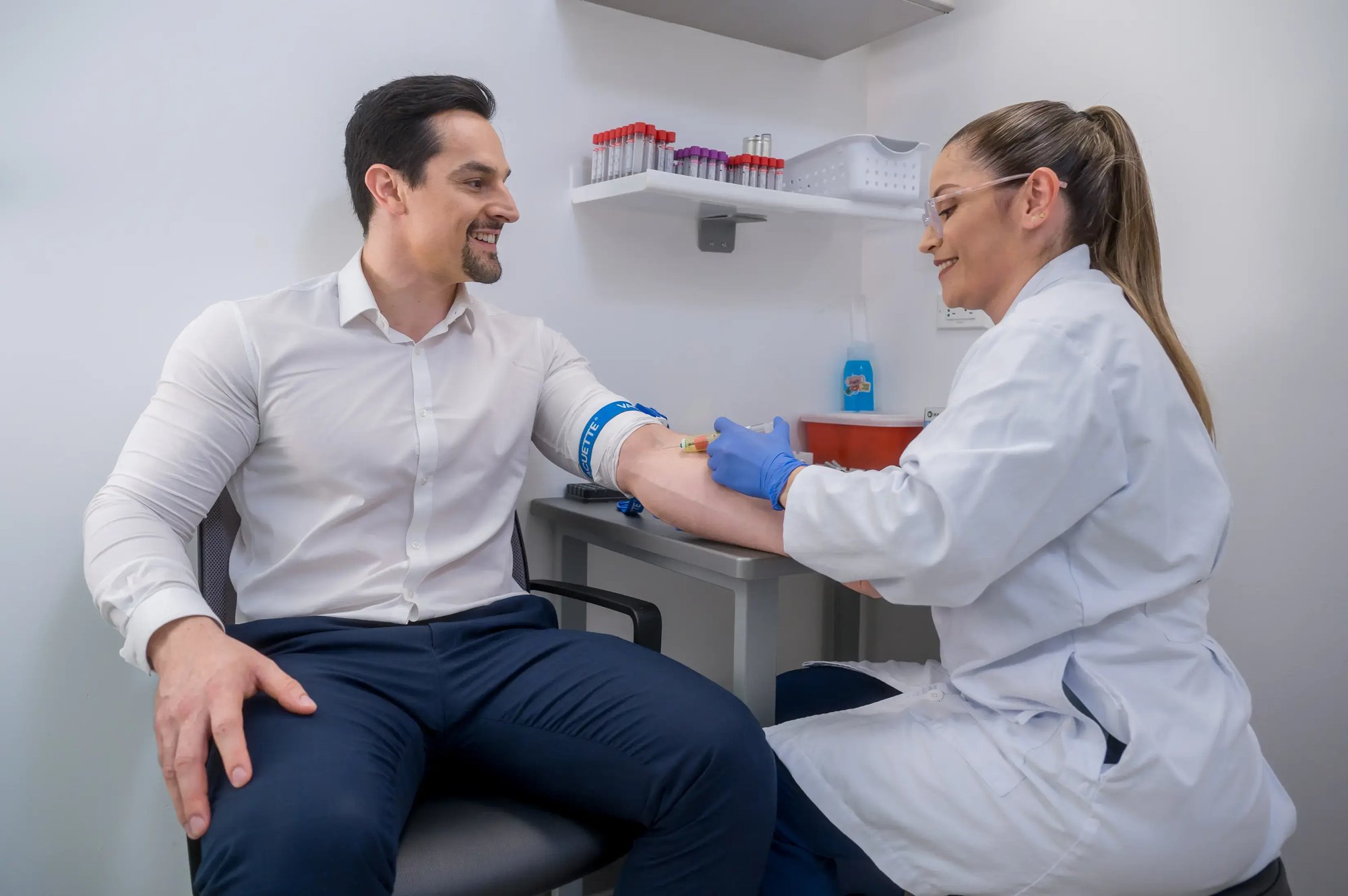 Health professional taking a blood sample from a man in a clinical office.