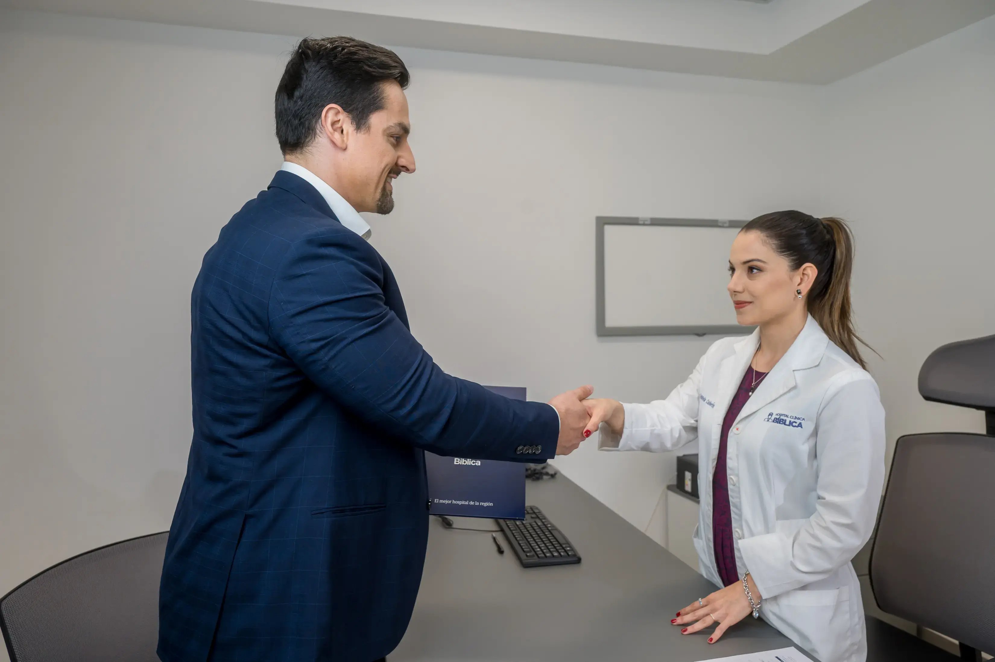 Médico estrechando la mano de un paciente en una consulta dentro de un consultorio.