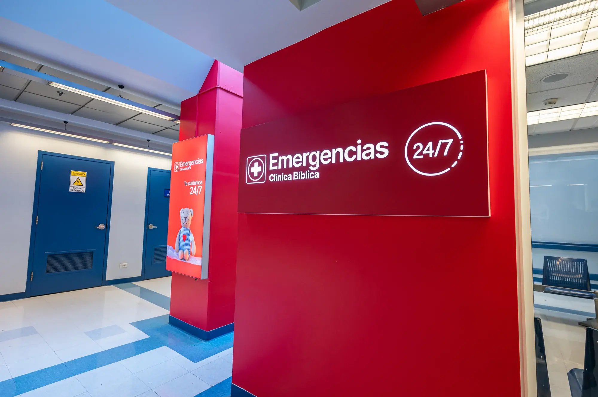 Ingreso a emergencias de hospital con letrero rojo que indica servicio 24/7.