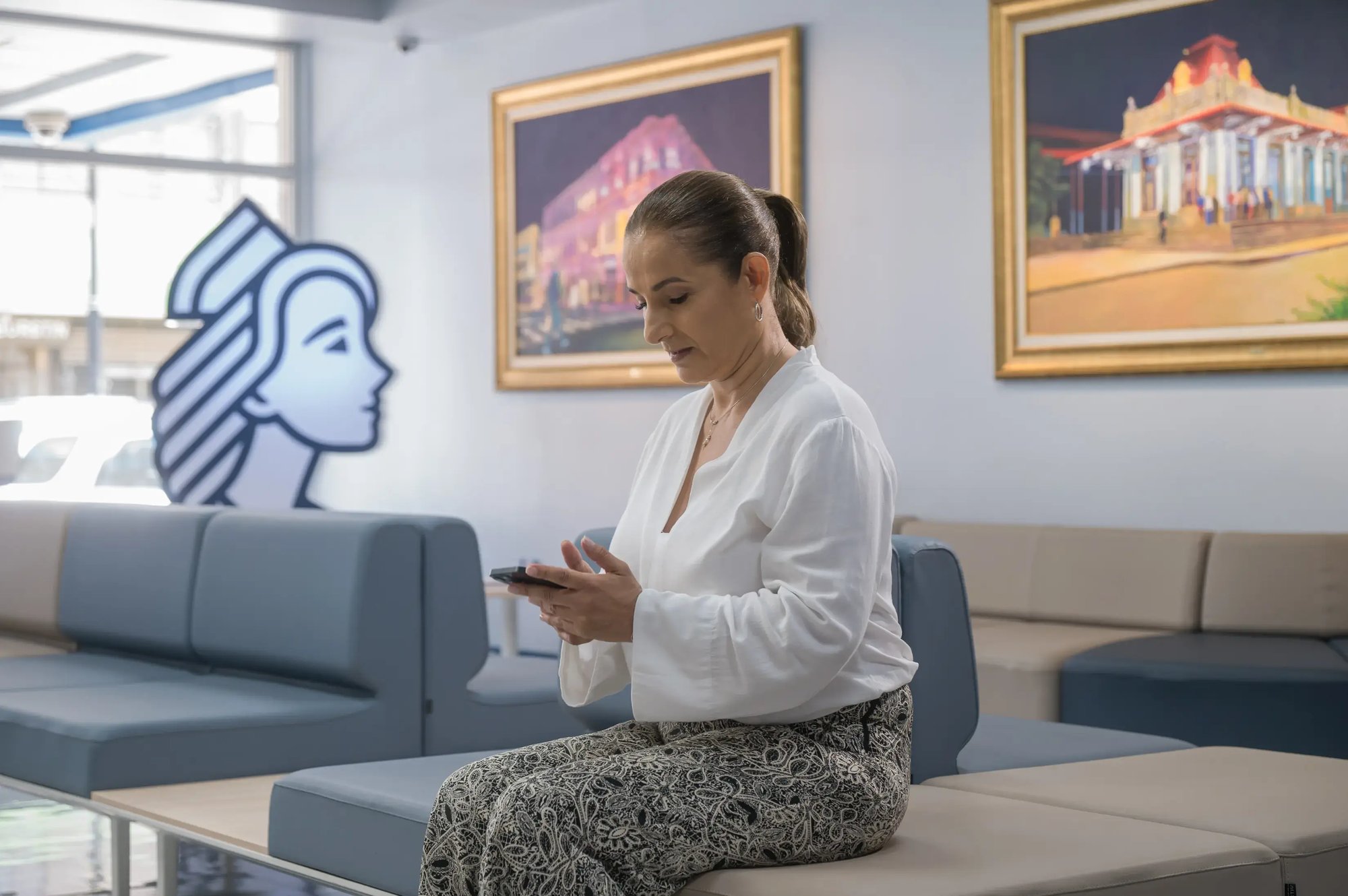 Woman sitting in a clinic waiting room while using her cell phone.