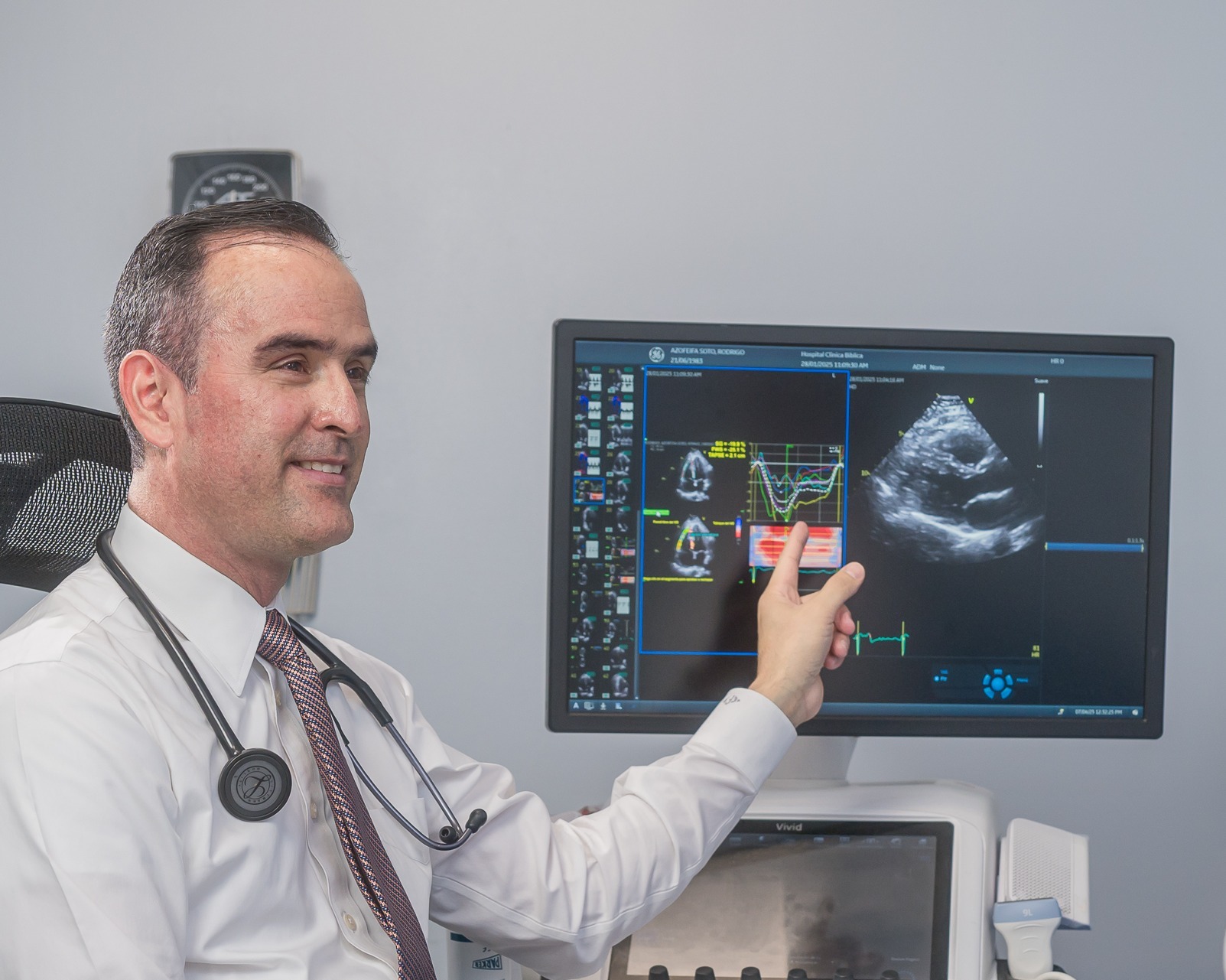 Cardiólogo mostrando resultados de ecocardiograma en monitor