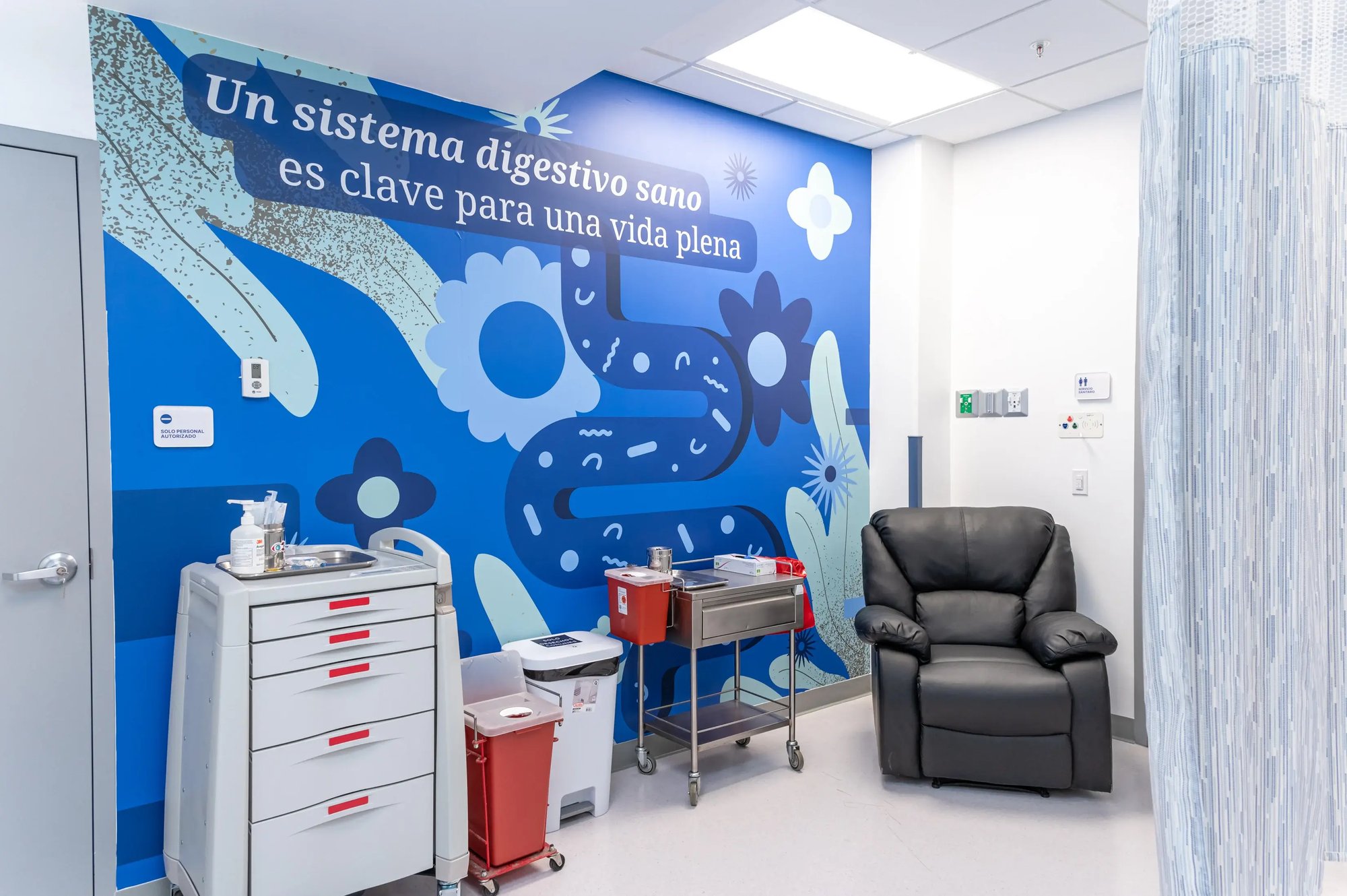 Sala médica con mural azul y mensaje sobre la importancia del sistema digestivo. Sala médica con mural azul y mensaje sobre la importancia del sistema digestivo.