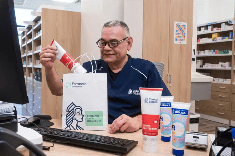Farmacéutico de Clínica Bíblica colocando crema en bolsa de farmacia
