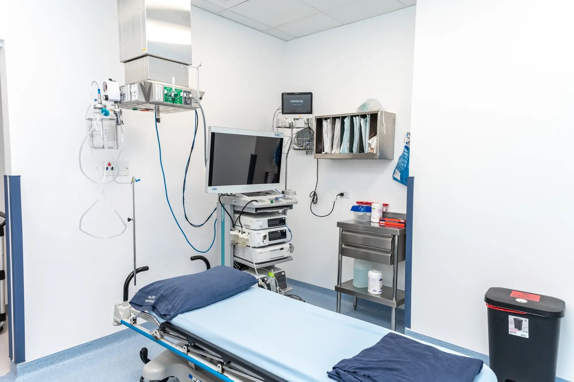 Sala de endoscopía equipada con monitor, cama y equipo médico. Sala de endoscopía equipada con monitor, cama y equipo médico.