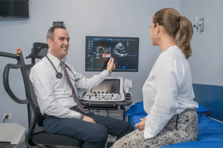 Cardiólogo mostrando resultados de ecocardiograma a paciente en consulta