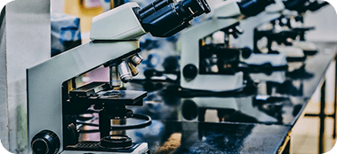 Microscopios alineados sobre mesa en laboratorio clínico.