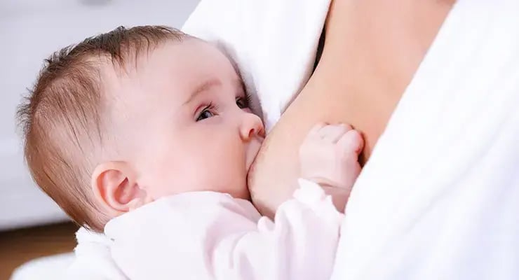 Bebé lactando en brazos de su madre durante la alimentación.