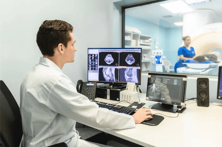 Physician observing magnetic resonance images on a control monitor.