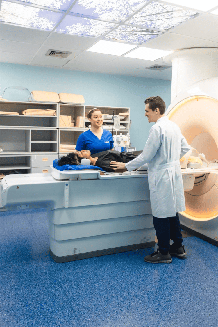 Patient lying down being prepared by medical personnel for an MRI study.