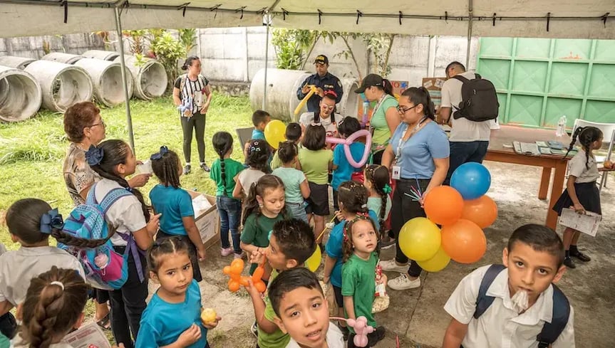 Niños participando en actividad comunitaria con globos y dinámicas