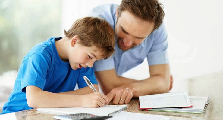 Adulto acompañando a un niño mientras escribe en un cuaderno sobre una mesa