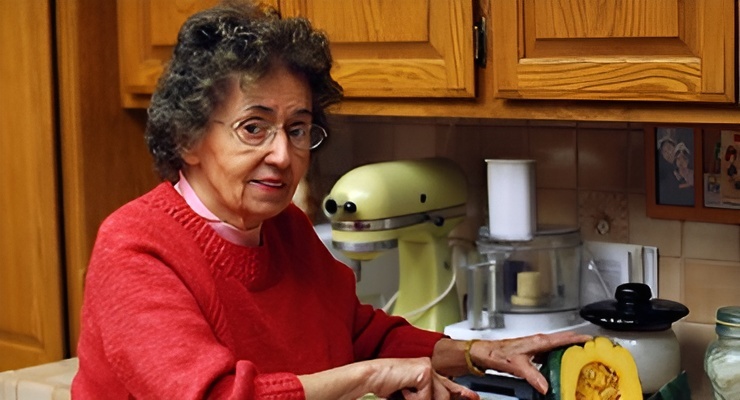 Persona adulta mayor preparando alimentos en la cocina.