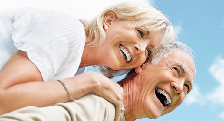 Pareja de adultos mayores sonriendo y disfrutando de un momento al aire libre.