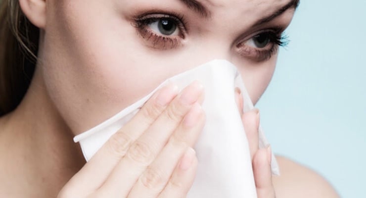 Mujer con pañuelo cubriendo nariz y boca por síntomas de alergia respiratoria