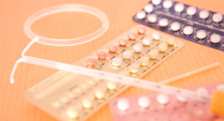 Dispositivos anticonceptivos de larga duración y pastillas anticonceptivas sobre una superficie de madera