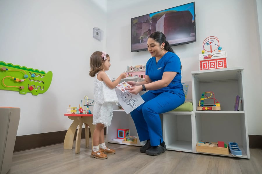 Especialista pediátrica interactuando con una niña en sala infantil de atención médica
