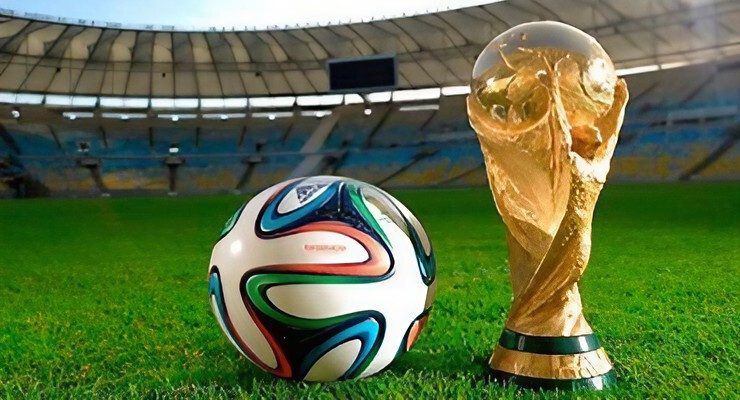 Balón de fútbol junto al trofeo de la Copa Mundial en un estadio