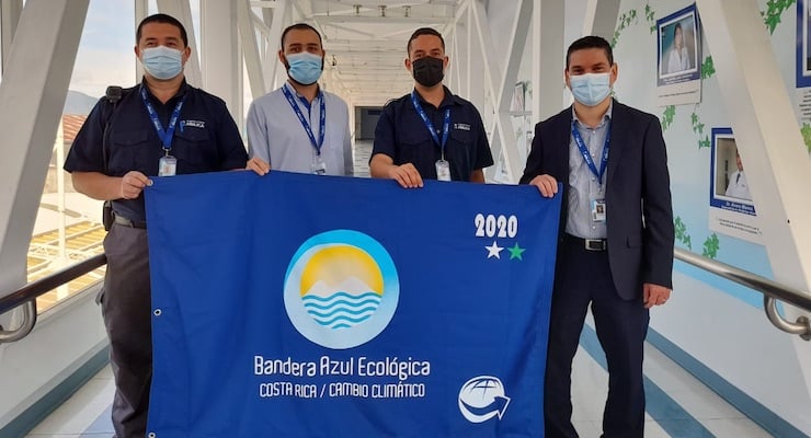 Colaboradores del Hospital Clínica Bíblica sostienen la Bandera Azul Ecológica por reconocimiento en cambio climático