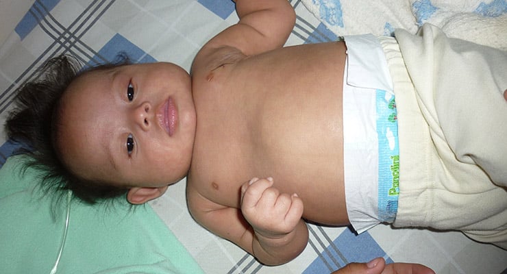 Bebé acostado boca arriba sobre una cama con pañal y pantalón