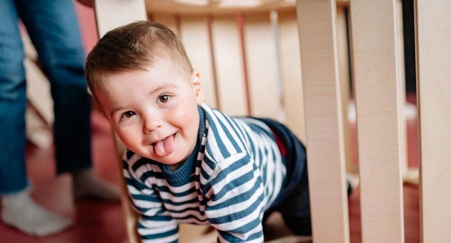Niño pequeño sacando la lengua mientras juega, permitiendo observar la zona del frenillo lingual durante una revisión pediátrica.