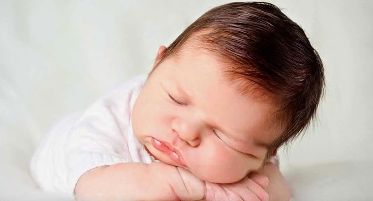 Bebé dormido apoyando la cabeza sobre sus brazos