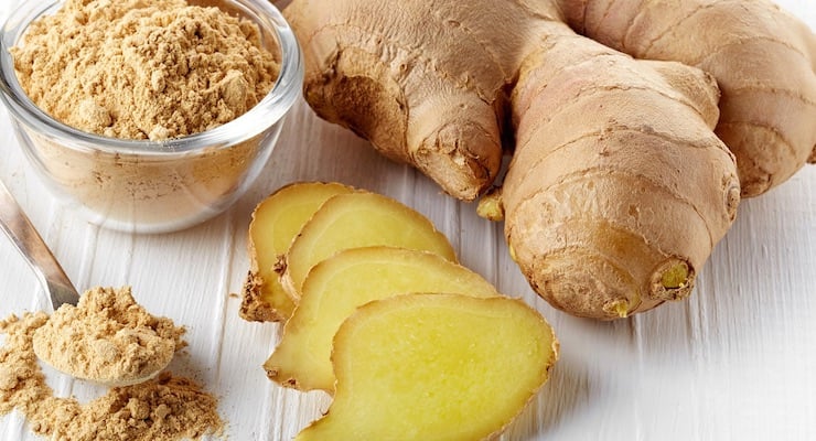 Raíz de jengibre fresco con rodajas y jengibre en polvo en recipiente