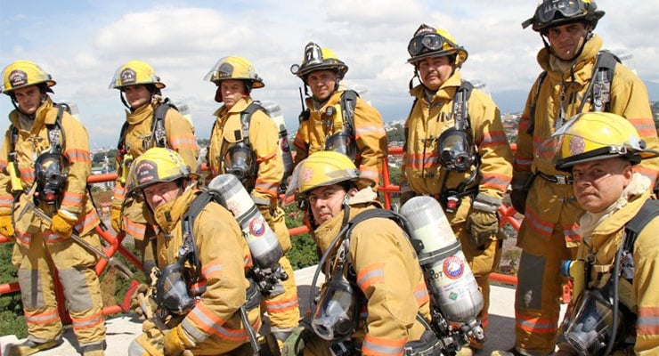 Grupo de bomberos equipados con trajes de protección y equipos de respiración durante un ejercicio o intervención.