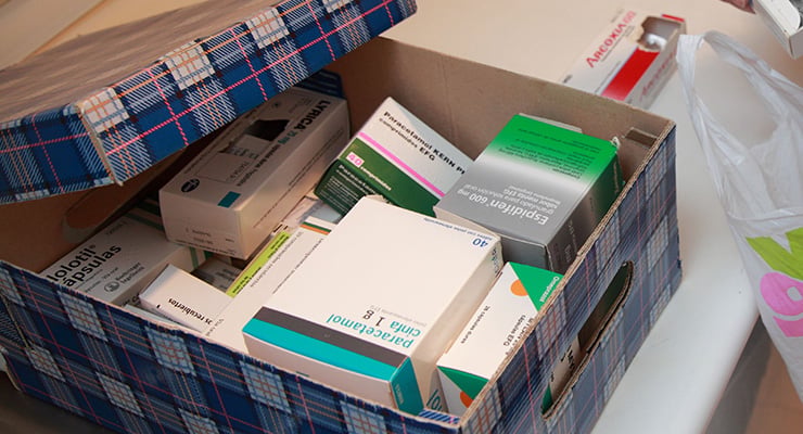 Caja de cartón abierta con diferentes cajas de medicamentos y productos farmacéuticos en su interior.