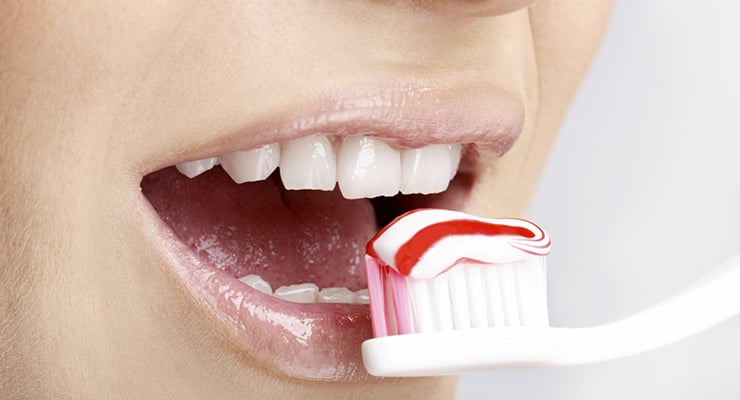 Boca abierta con un cepillo de dientes y pasta dental frente a los dientes