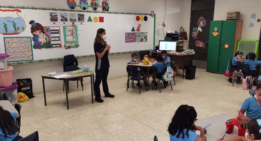 Profesional del Hospital Clínica Bíblica brinda charla de educación bucodental a niños en aula de centro educativo.