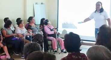 Grupo de personas adultas asistiendo a una charla con presentación proyectada.