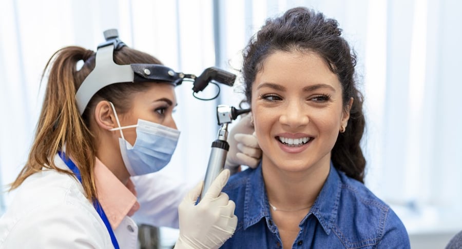 Especialista realiza un examen de otoscopia a una paciente sonriente para evaluar su salud auditiva.