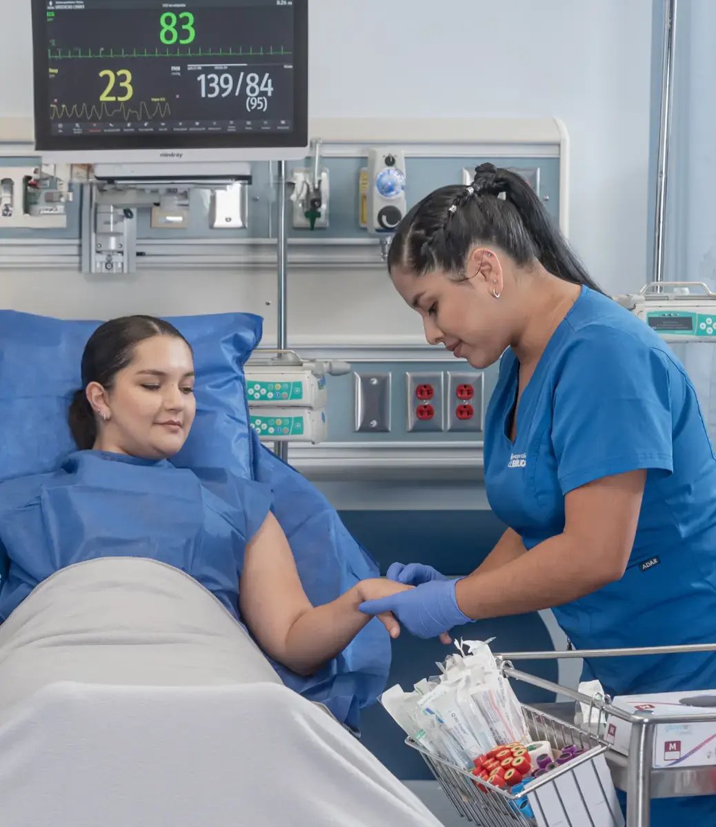 Nurse at Clínica Bíblica attending to a hospitalized patient in the ward with vital signs monitor.