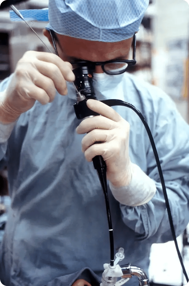Médico especialista del Hospital Clínica Bíblica realizando un procedimiento médico especializado con un endoscopio flexible en el quirófano.