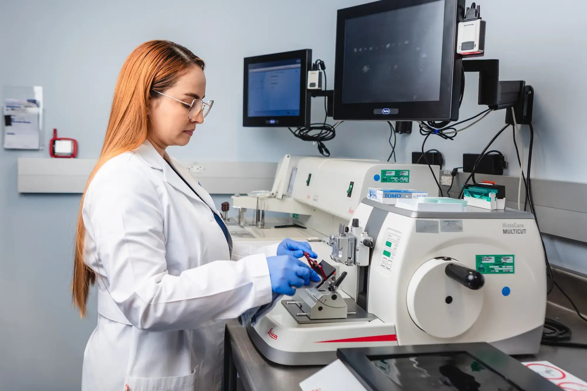 Especialista de laboratorio en el Hospital Clínica Bíblica colocando una muestra médica dentro de un equipo especializado para su análisis en el departamento de patología.