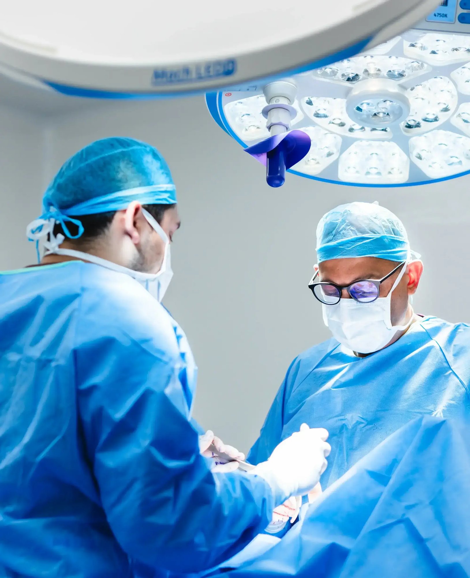 Specialist surgeons performing a high-complexity surgical procedure under advanced operating room lights at Hospital Clinica Biblica, Costa Rica.