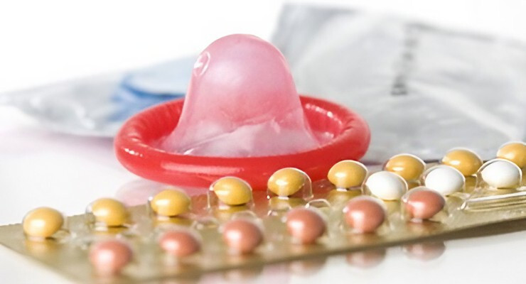 Condón masculino junto a un blíster de pastillas anticonceptivas sobre una superficie