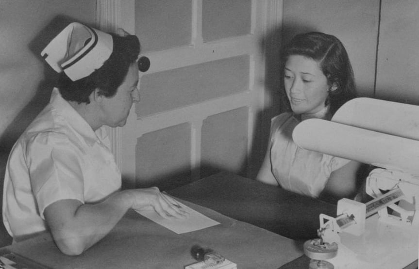 Enfermera del Hospital Clínica Bíblica brindando consulta a una paciente, fotografía histórica.