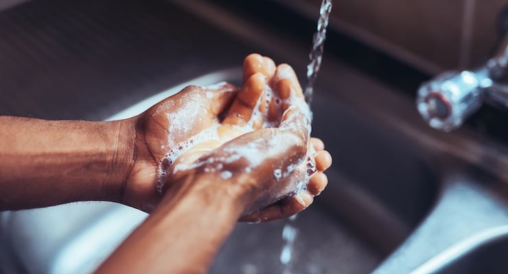 Persona lavándose las manos con agua y jabón bajo el grifo