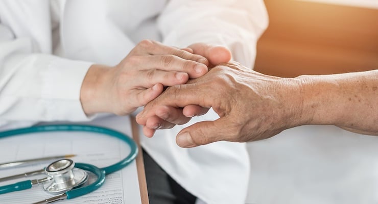 Médico tomando la mano de un adulto mayor durante consulta médica