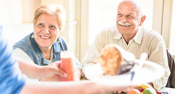 Pareja de adultos mayores compartiendo alimentos y bebidas en la mesa