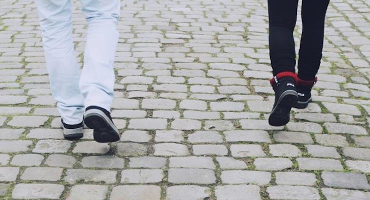 Dos personas caminando sobre una calle empedrada durante el distanciamiento social