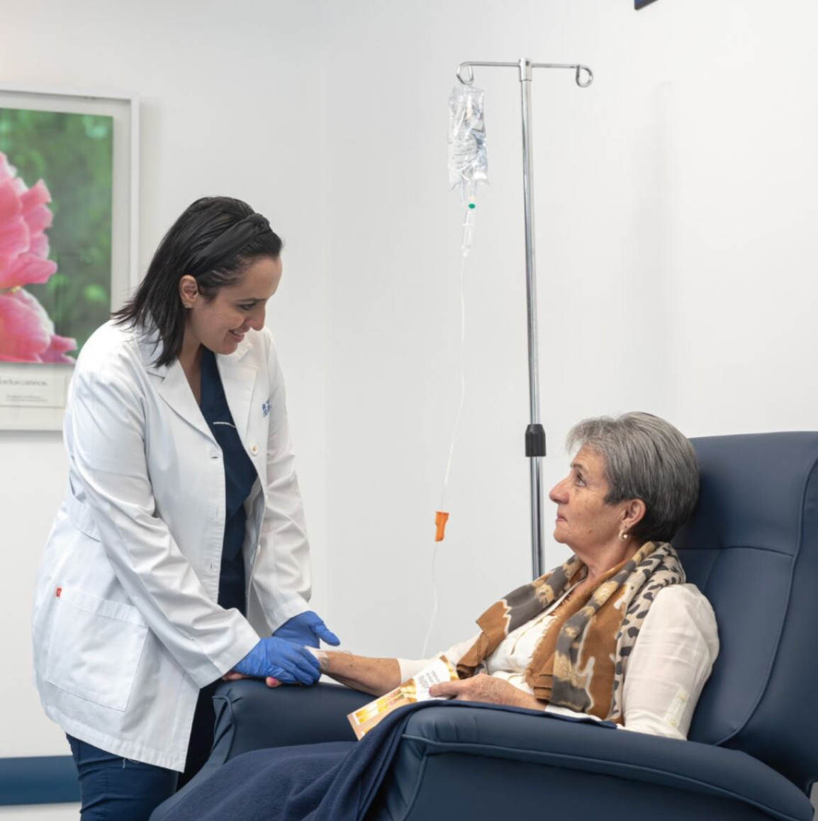 Doctor attending to elderly patient during intravenous treatment at clinic