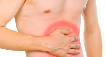 Hombre con la mano sobre el abdomen con zona enrojecida que indica dolor