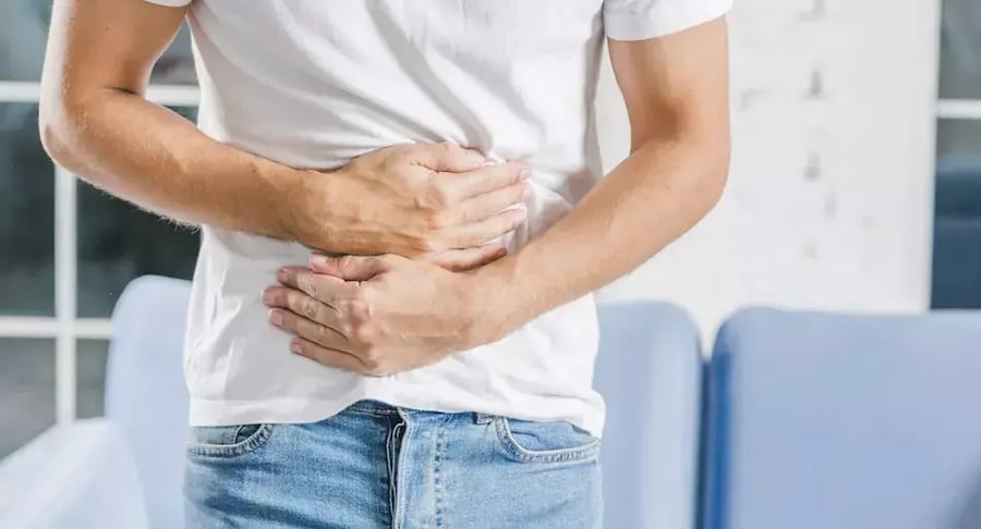Hombre con dolor abdominal sosteniendo la parte baja del abdomen con las manos