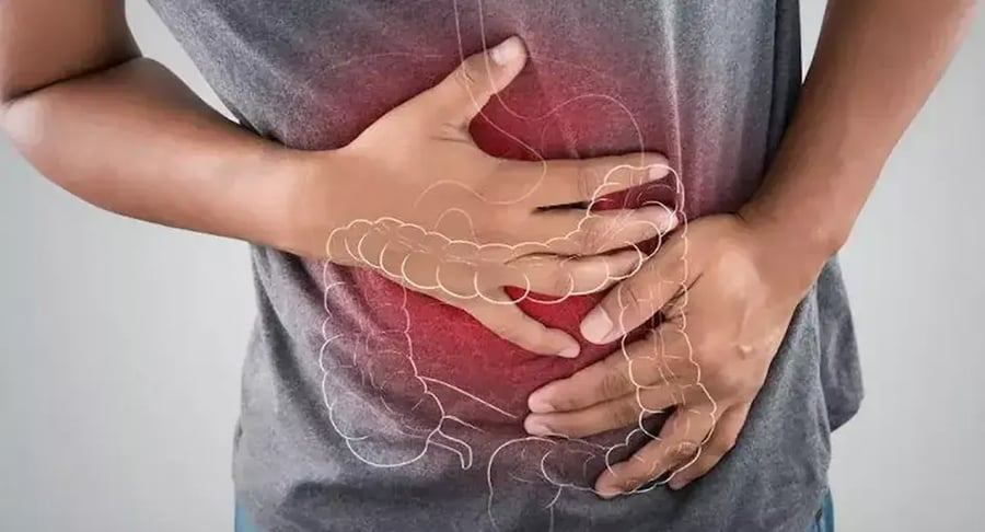 Persona con dolor abdominal intenso señalado en el área intestinal