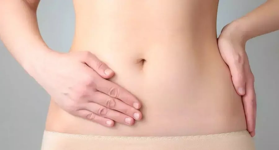 Mujer con dolor abdominal sosteniendo el costado de su vientre bajo