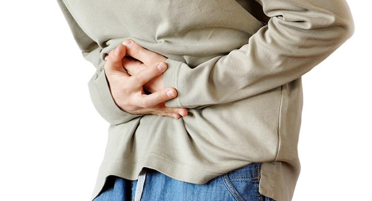 Persona sujetándose el abdomen con ambas manos por malestar estomacal