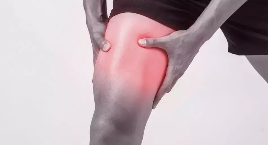 Persona con dolor muscular en la pierna, zona del muslo resaltada en rojo